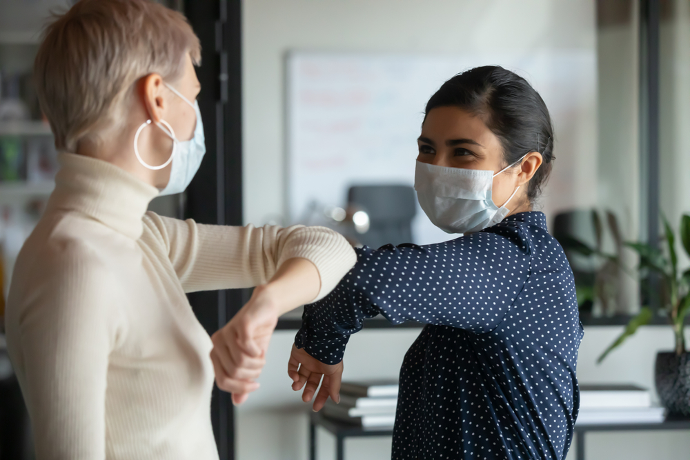 Two women greet each other during a pandemic.